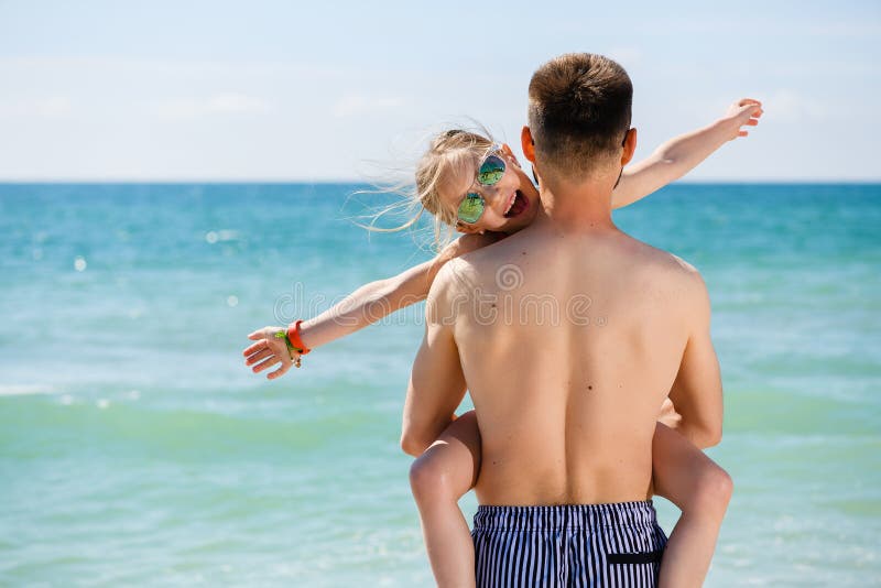 Il giovane papà tiene la figlia in mare fotografia stock