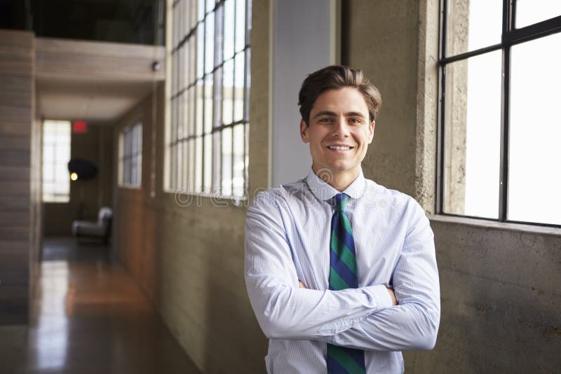 Il giovane uomo d'affari bianco sta sorridere con le armi attraversate fotografie stock Il giovane uomo d'affari bianco sta sorridere con le armi attraversate fotografie stock