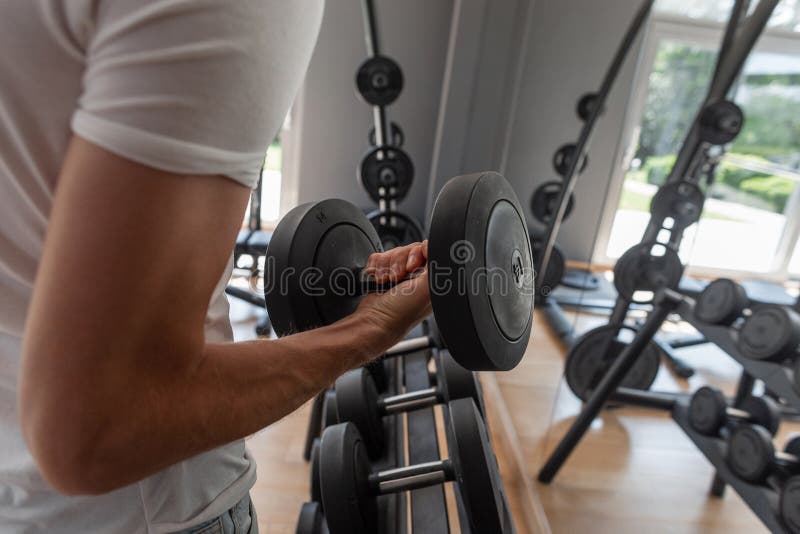 Il giovane uomo di sport in una maglietta d'avanguardia bianca prende una testa di legno Il tipo sta preparandosi nella palestra fotografia stock libera da diritti Il giovane uomo di sport in una maglietta d'avanguardia bianca prende una testa di legno Il tipo sta preparandosi nella palestra fotografia stock libera da diritti