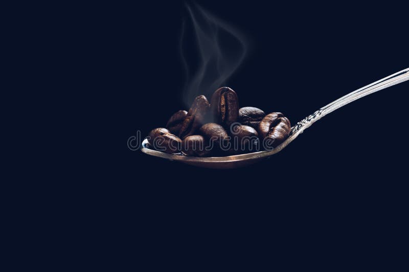 Il grano ha arrostito il cucchiaio di caffè con fumo su fondo scuro con ombreggiatura fotografia stock Il grano ha arrostito il cucchiaio di caffè con fumo su fondo scuro con ombreggiatura fotografia stock