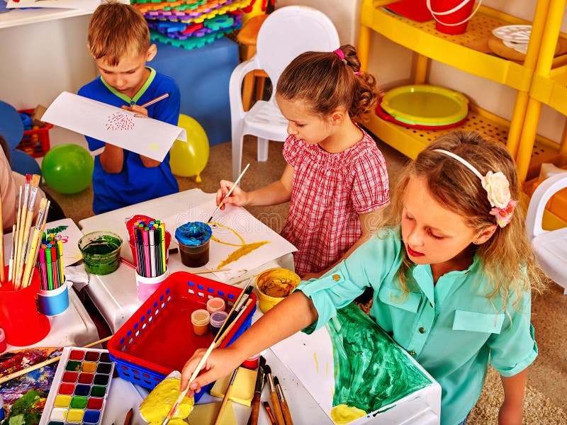 Il gruppo di bambini disegna le immagini nel piccolo asilo fotografia stock Il gruppo di bambini disegna le immagini nel piccolo asilo fotografia stock