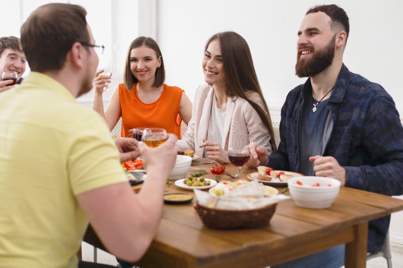 Il gruppo di giovani felici alla tavola di cena, amici fa festa immagini stock Il gruppo di giovani felici alla tavola di cena, amici fa festa immagini stock