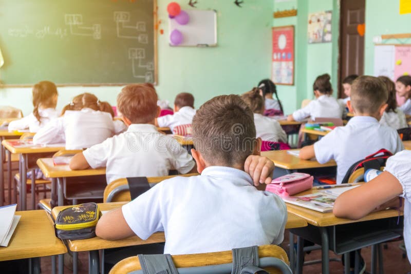 Il gruppo di scuola scherza la seduta ed ascoltare l'insegnante in classro fotografia stock libera da diritti Il gruppo di scuola scherza la seduta ed ascoltare l'insegnante in classro fotografia stock libera da diritti
