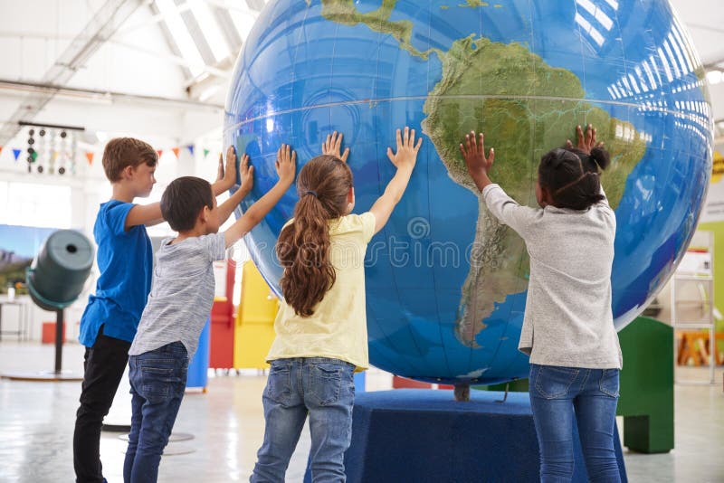 Il gruppo di scuola scherza la tenuta del globo gigante ad un centro di scienza fotografia stock Il gruppo di scuola scherza la tenuta del globo gigante ad un centro di scienza fotografia stock