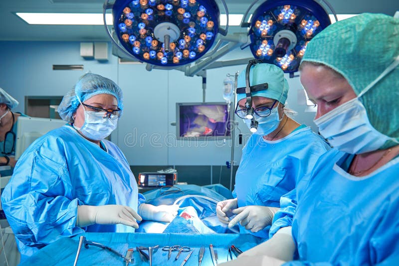Il gruppo di un chirurgo in uniforme realizza un'operazione su un paziente ad una clinica cardiaca della chirurgia Medicina moder fotografia stock Il gruppo di un chirurgo in uniforme realizza un'operazione su un paziente ad una clinica cardiaca della chirurgia Medicina moder fotografia stock