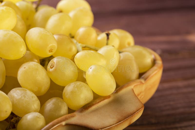Il gruppo di uva verde fresca saporita si chiude su in una ciotola su fondo di legno fotografia stock libera da diritti Il gruppo di uva verde fresca saporita si chiude su in una ciotola su fondo di legno fotografia stock libera da diritti