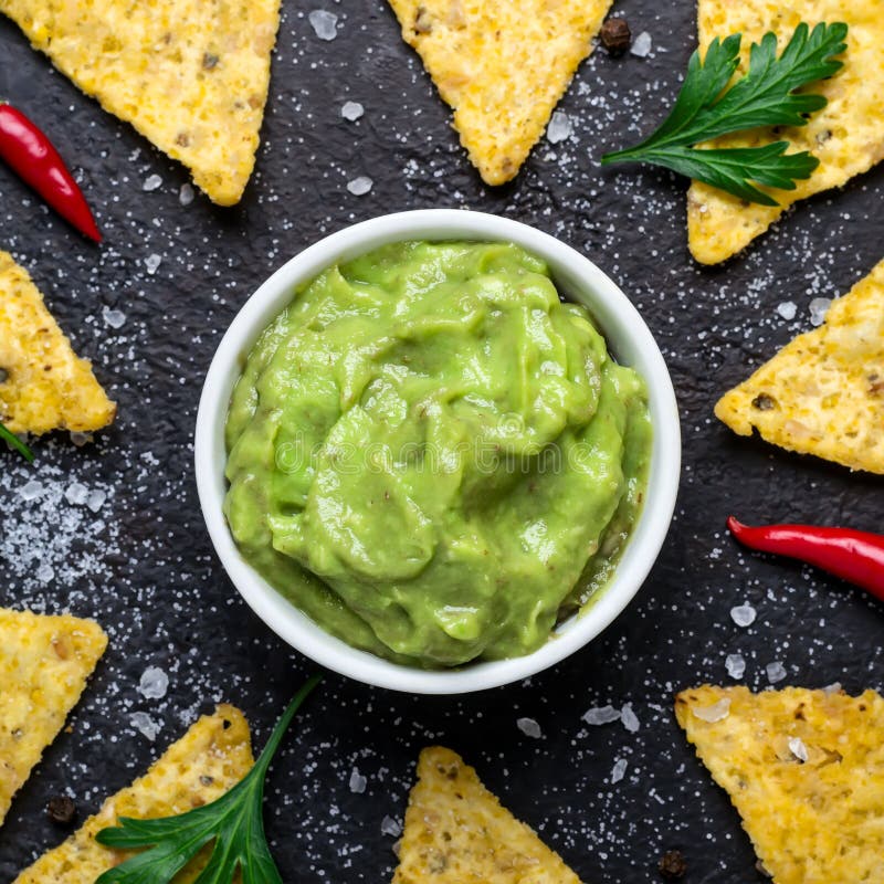 Il guacamole ed il cereale scheggia il primo piano Alimento dell'America latina tradizionale su fondo nero immagini stock libere da diritti Il guacamole ed il cereale scheggia il primo piano Alimento dell'America latina tradizionale su fondo nero immagini stock libere da diritti