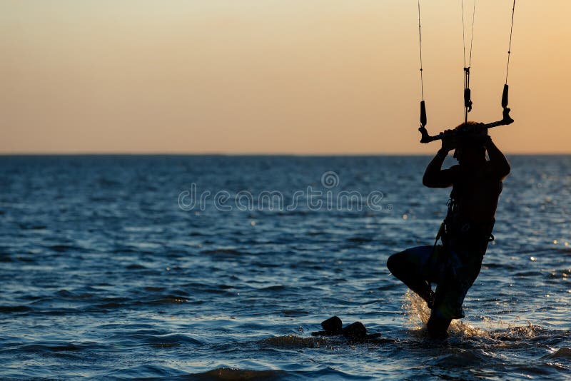 Il kitter professionale prepara per la corsa contro il contesto di bello tramonto fotografia stock Il kitter professionale prepara per la corsa contro il contesto di bello tramonto fotografia stock
