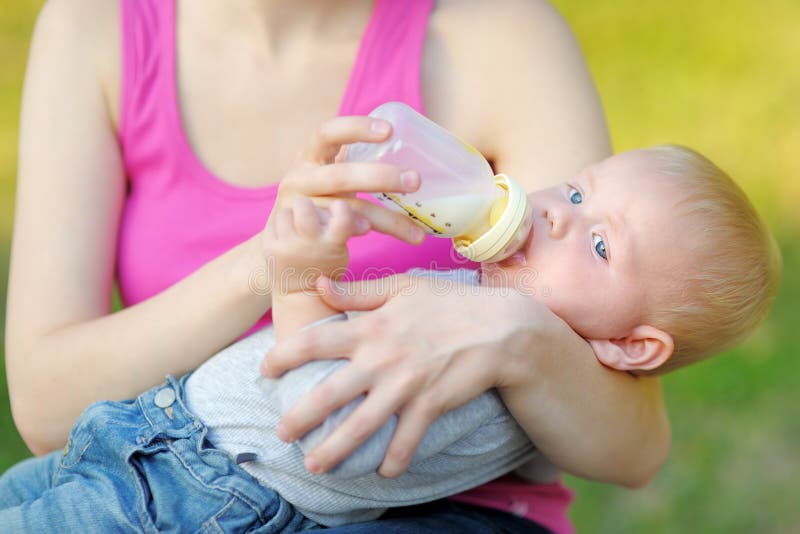 Il latte alimentare del bambino da imbottiglia le mani della madre immagine stock libera da diritti Il latte alimentare del bambino da imbottiglia le mani della madre immagine stock libera da diritti
