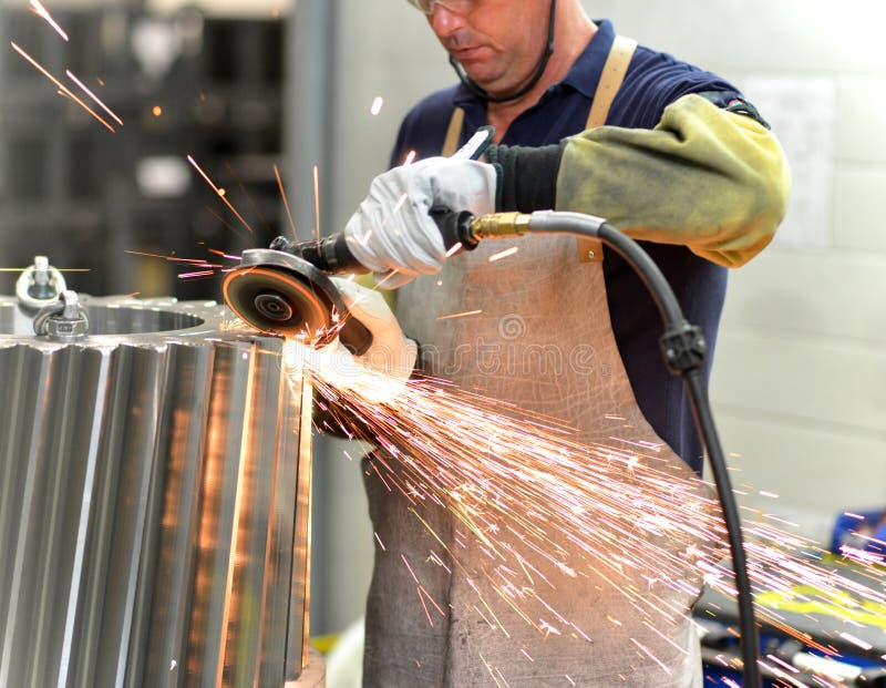 Il lavoratore con una macchina per la frantumazione elabora una ruota di ingranaggio - producti fotografia stock Il lavoratore con una macchina per la frantumazione elabora una ruota di ingranaggio - producti fotografia stock