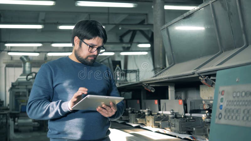 Il lavoratore maschio sta osservando una stampatrice di funzionamento