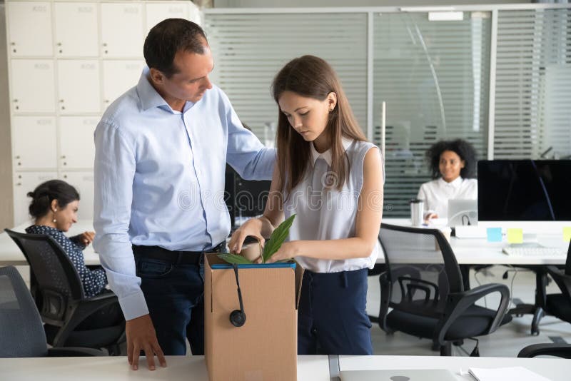 Il licenziamento sostenente dell'uomo d'affari ha rovesciato gli effetti personali del pacchetto della donna in scatola di carton immagine stock libera da diritti Il licenziamento sostenente dell'uomo d'affari ha rovesciato gli effetti personali del pacchetto della donna in scatola di carton immagine stock libera da diritti