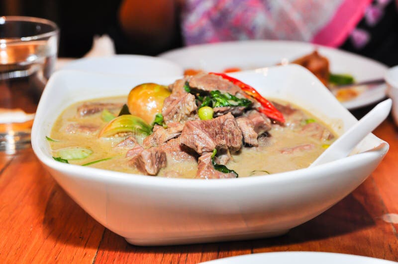 Il manzo verde tailandese del curry in grande ciotola bianca alla tavola del ristorante immagine stock libera da diritti Il manzo verde tailandese del curry in grande ciotola bianca alla tavola del ristorante immagine stock libera da diritti