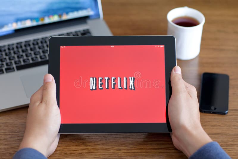 Il maschio passa il iPad della tenuta con il app Netflix sullo schermo in di immagine stock Il maschio passa il iPad della tenuta con il app Netflix sullo schermo in di immagine stock