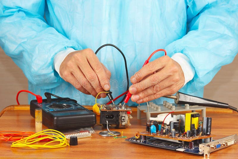 Il Master controlla il bordo elettronico con il multimetro nell'officina di servizio fotografia stock