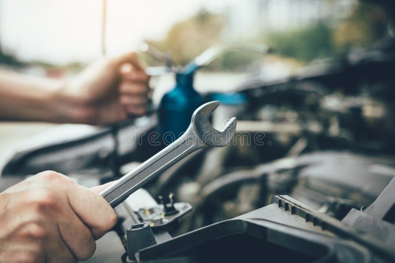 Il meccanico di automobile asiatico giudica una chiave e una bottiglia dell'olio di richiamo, pronte a riparare l'automobile fotografia stock Il meccanico di automobile asiatico giudica una chiave e una bottiglia dell'olio di richiamo, pronte a riparare l'automobile fotografia stock
