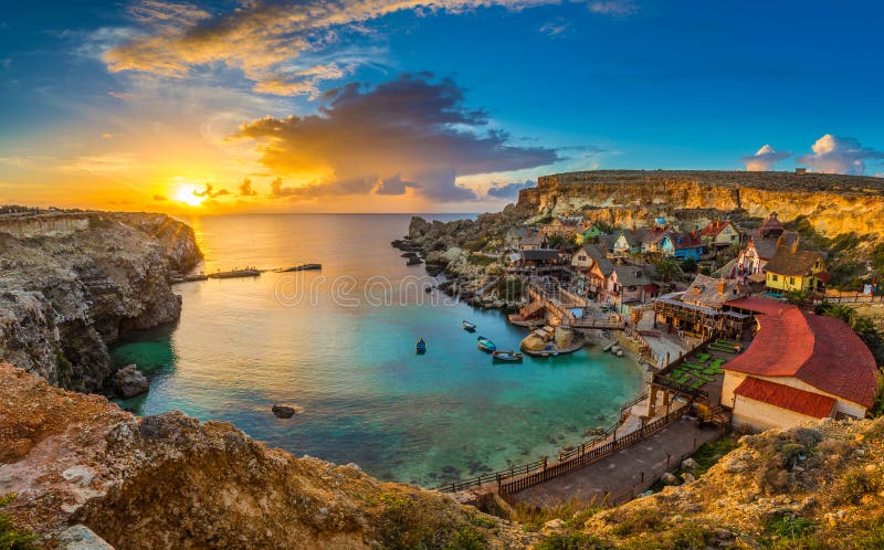 Il-Mellieha Malta - panorama- horisontsikt av den berömda Popeye byn på ankarfjärden på solnedgången