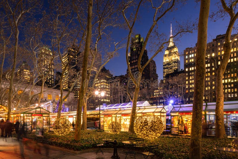 Il mercato natalizio di Bryant Park Winter Village in serata con l'Empire State Building New York City, Manhattan, Midtown