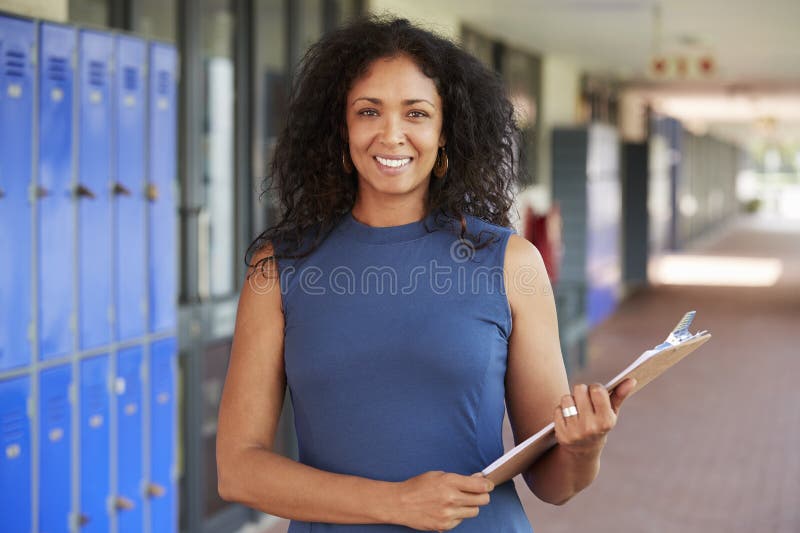 Il mezzo ha invecchiato l'insegnante femminile nero che sorride in corridoio della scuola