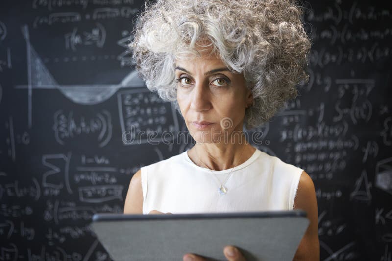Il mezzo ha invecchiato la donna accademica che per mezzo della compressa che guarda alla macchina fotografica immagini stock Il mezzo ha invecchiato la donna accademica che per mezzo della compressa che guarda alla macchina fotografica immagini stock