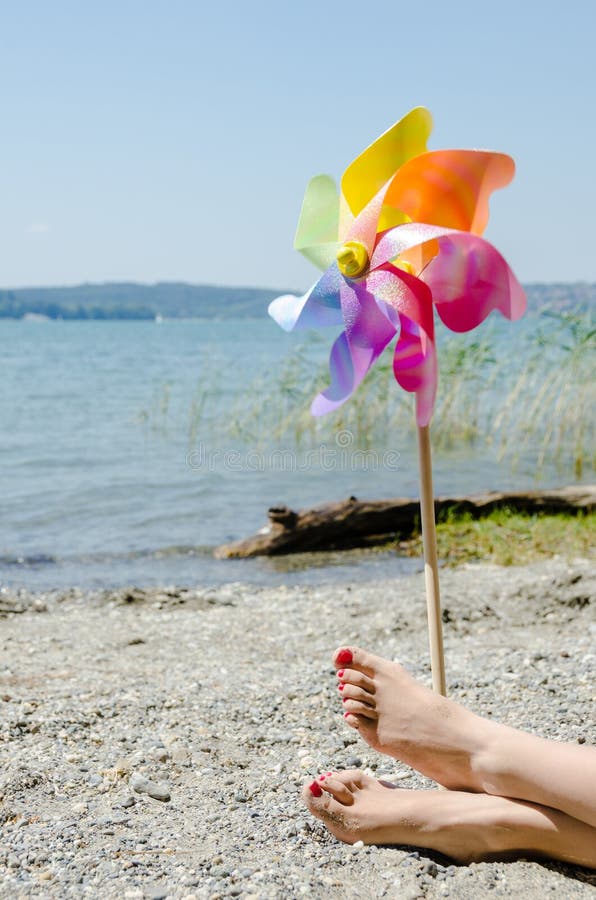 Il mulino a vento e le gambe femminili dei bambini alla spiaggia fotografie stock libere da diritti Il mulino a vento e le gambe femminili dei bambini alla spiaggia fotografie stock libere da diritti