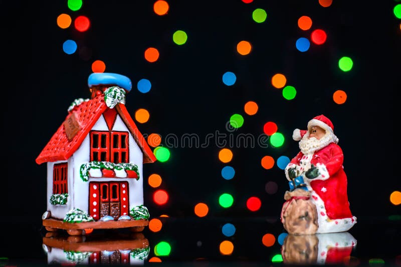 Il Natale rappresenta con Santa e la casa su un fondo delle luci colorate immagine stock Il Natale rappresenta con Santa e la casa su un fondo delle luci colorate immagine stock