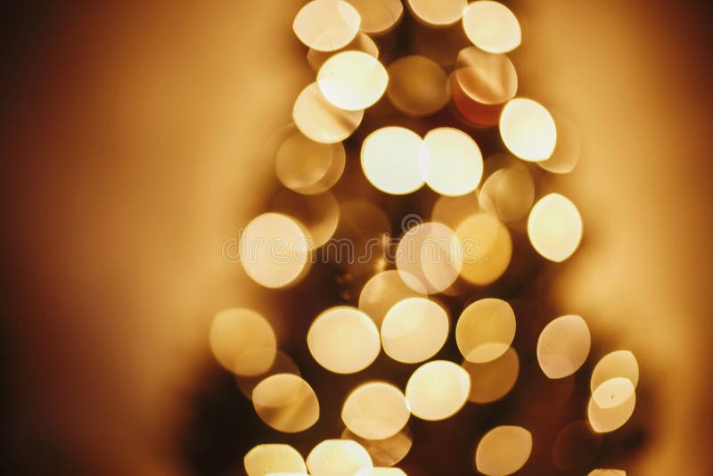 Christmas abstract background, beautiful christmas tree golden lights defocused bokeh. blur of yellow glowing illumination in festive room. decor for winter holidays. atmospheric moment. Christmas abstract background, beautiful christmas tree golden lights defocused bokeh. blur of yellow glowing illumination in festive room. decor for winter holidays. atmospheric moment