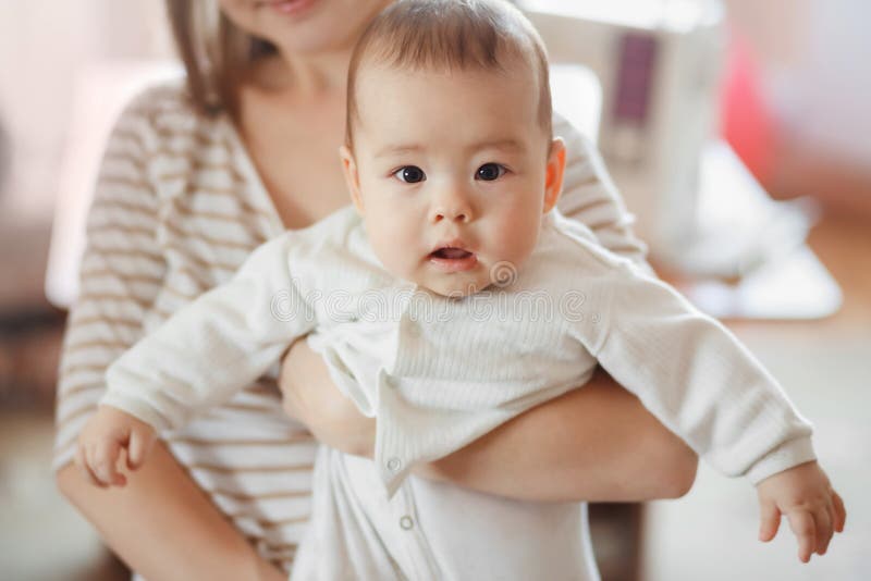 Il neonato piccolo sveglio in armi della mamma su aria Madre ed infante, cura infantile, crescita dei bambini Interessato sguardi fotografia stock libera da diritti Il neonato piccolo sveglio in armi della mamma su aria Madre ed infante, cura infantile, crescita dei bambini Interessato sguardi fotografia stock libera da diritti
