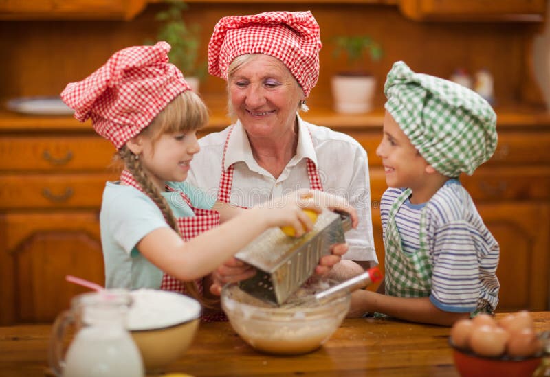Il nipote e la nipote baciano la loro nonna nella cucina immagine stock Il nipote e la nipote baciano la loro nonna nella cucina immagine stock