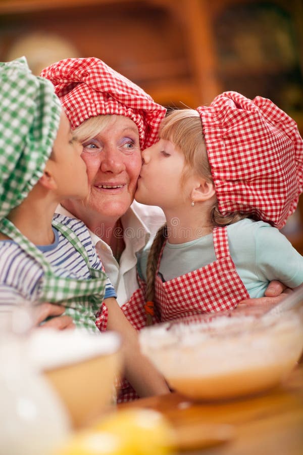 Il nipote e la nipote baciano la loro nonna nella cucina immagini stock libere da diritti Il nipote e la nipote baciano la loro nonna nella cucina immagini stock libere da diritti