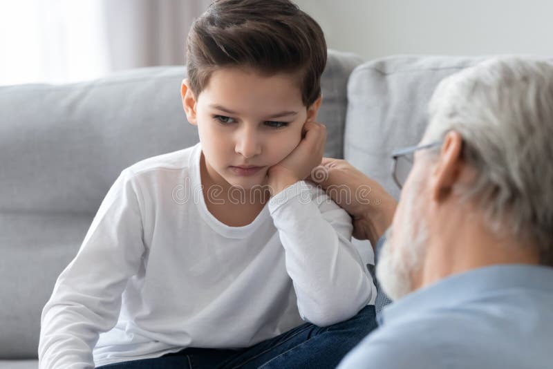 Il nonno premuroso si calmava, parlava con il nipotino sconvolto immagine stock