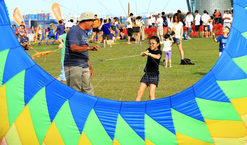 Grandfather is teaching granddaughter how to fly one big kite at marina barrage in singapore. Grandfather is teaching granddaughter how to fly one big kite at marina barrage in singapore