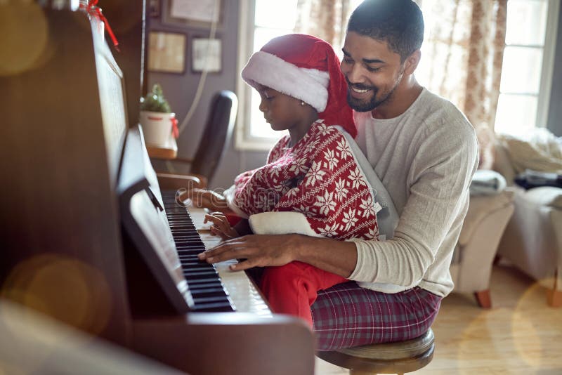 Il padre con la ragazza del bambino sul Natale gioca la musica sul piano