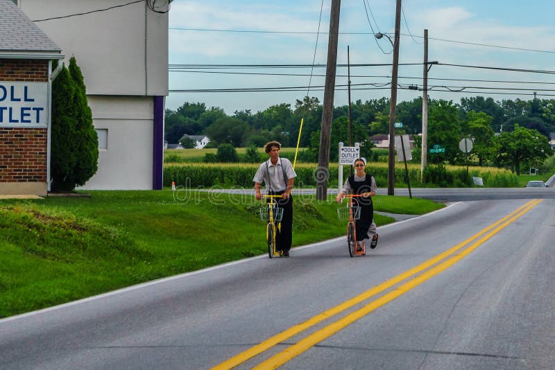 Il paese di Amish, di Ronks, il PA 27 Julay 2017 un uomo e una guida della donna su Amish disegnano i motorini del ` immagine stock Il paese di Amish, di Ronks, il PA 27 Julay 2017 un uomo e una guida della donna su Amish disegnano i motorini del ` immagine stock