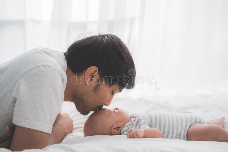 Il papà asiatico bacia il suo bambino sulla fronte fotografie stock libere da diritti Il papà asiatico bacia il suo bambino sulla fronte fotografie stock libere da diritti