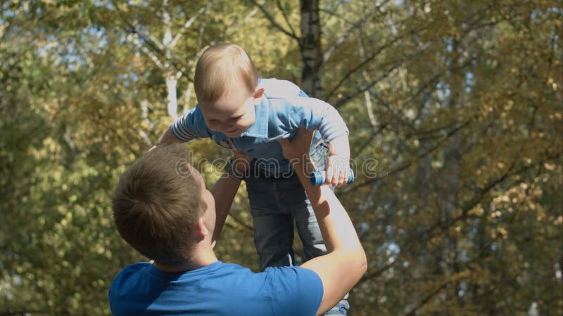 Il papà lancia il figlio nell'aria in un parco di autunno Famiglia felice fotografia stock Il papà lancia il figlio nell'aria in un parco di autunno Famiglia felice fotografia stock