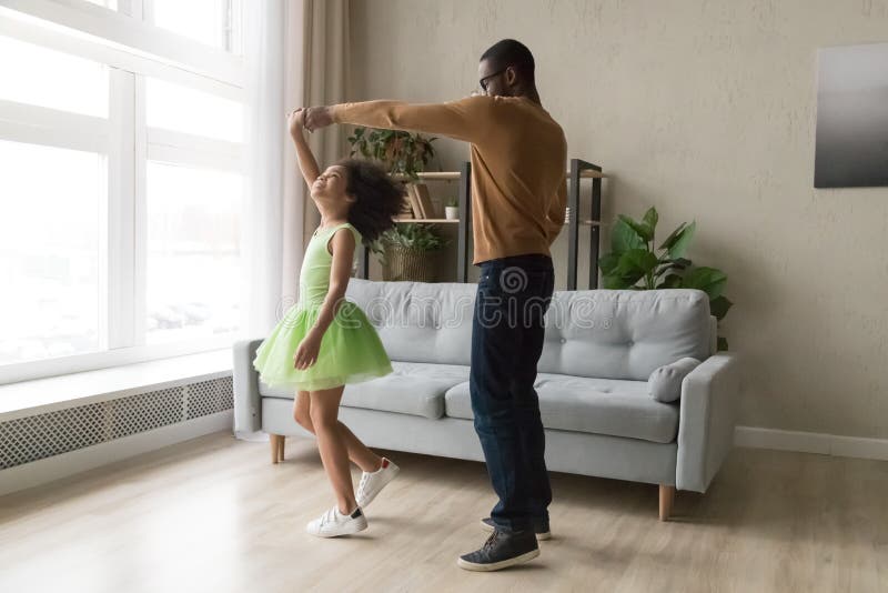 Il papà nero balla con la figlia felice in abito verde