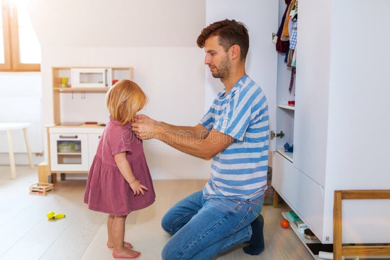 Il papà sta aiutando la figlia del bambino a vestiresi