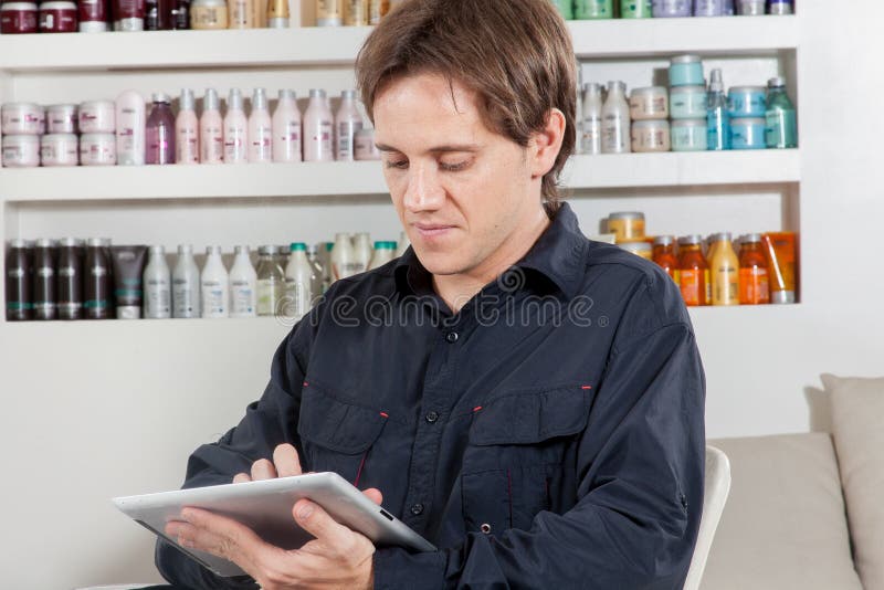 Il parrucchiere legge dentro il ipad fotografie stock libere da diritti Il parrucchiere legge dentro il ipad fotografie stock libere da diritti