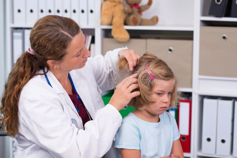 Il pediatra femminile in cappotto bianco del laboratorio ha esaminato il piccolo paziente immagine stock Il pediatra femminile in cappotto bianco del laboratorio ha esaminato il piccolo paziente immagine stock