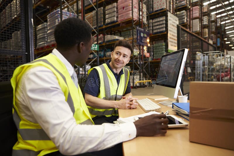 Il personale discute la logistica del magazzino in un ufficio in loco immagine stock Il personale discute la logistica del magazzino in un ufficio in loco immagine stock