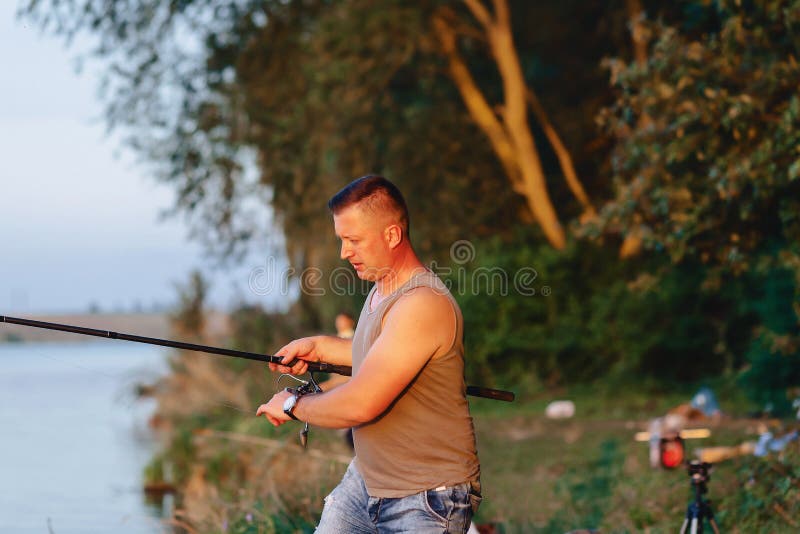 Il pescatore prepara la rottura per la carpa di cattura nel lago di estate immagini stock libere da diritti Il pescatore prepara la rottura per la carpa di cattura nel lago di estate immagini stock libere da diritti