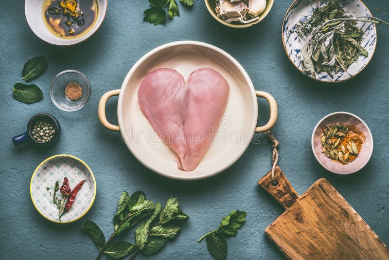Il petto di pollo nella forma del cuore in vaso con la cottura degli ingredienti lancia su fondo grigio, vista superiore fotografia stock Il petto di pollo nella forma del cuore in vaso con la cottura degli ingredienti lancia su fondo grigio, vista superiore fotografia stock