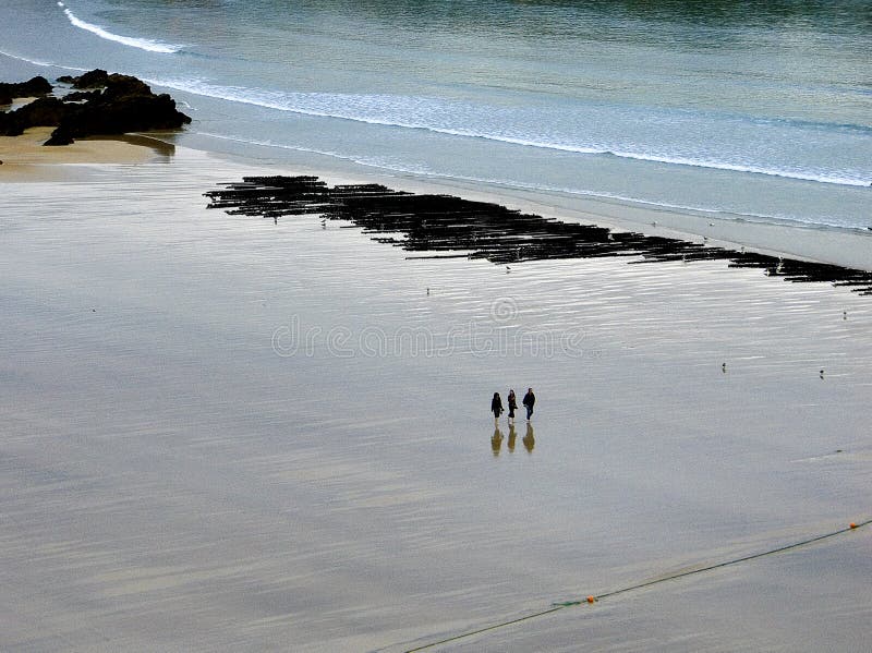 Il piede nudo della passeggiata di tre ragazze attraverso la spiaggia di Newquay, in Cornovaglia, a fine giornata come la marea p immagini stock Il piede nudo della passeggiata di tre ragazze attraverso la spiaggia di Newquay, in Cornovaglia, a fine giornata come la marea p immagini stock