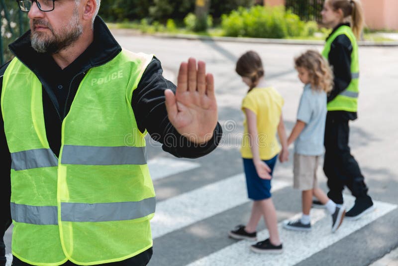 Il poliziotto con un giubbotto riflettente alza la mano per fermare l'auto fotografia stock libera da diritti
