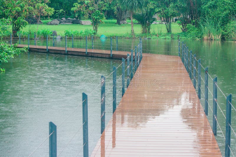 Il ponte di legno lungo attraversa il lago in parco pubblico circondato con naturale verde fotografia stock Il ponte di legno lungo attraversa il lago in parco pubblico circondato con naturale verde fotografia stock