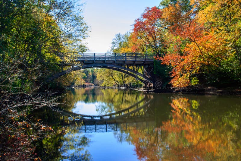 Il ponte ed il fogliame di caduta hanno riflesso nel fiume del mulino immagine stock Il ponte ed il fogliame di caduta hanno riflesso nel fiume del mulino immagine stock