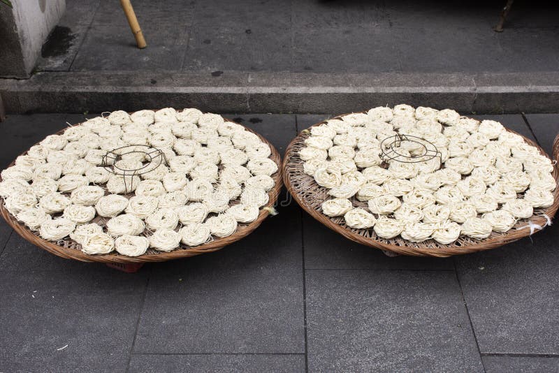 Il popolo cinese ha prodotto a tagliatella le tagliatelle asciugantesi casalinghe dell'uovo all'aperto su tessuto o sul canestro immagini stock Il popolo cinese ha prodotto a tagliatella le tagliatelle asciugantesi casalinghe dell'uovo all'aperto su tessuto o sul canestro immagini stock