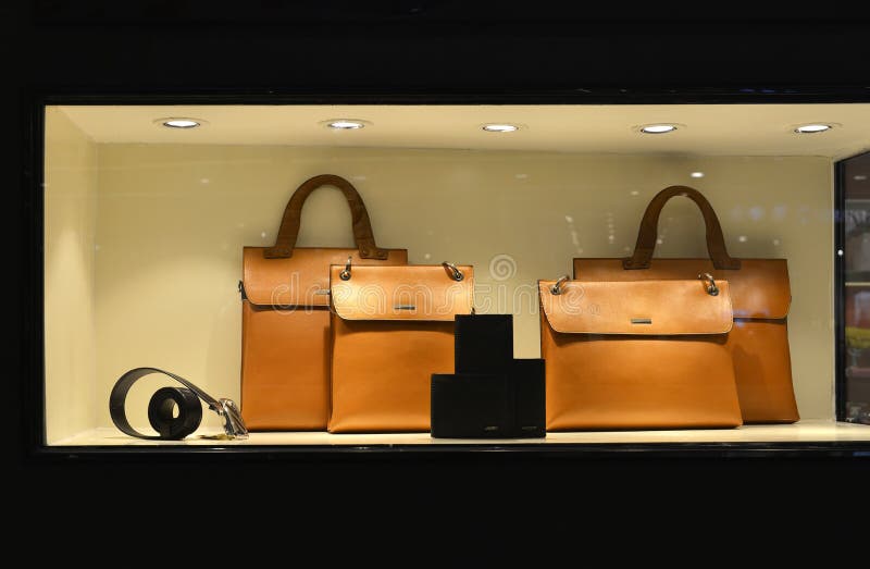 Il portafoglio di cuoio di lusso della cinghia della borsa nella finestra del negozio si è acceso dalle luci principali