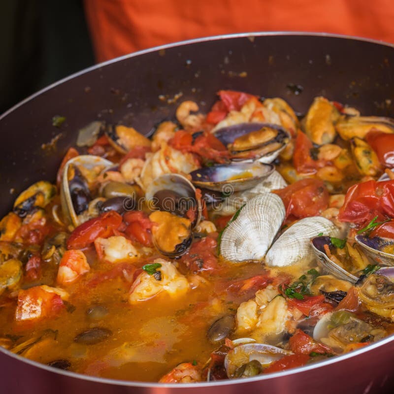 Il primo piano della padella con il piatto dei frutti di mare ha cucinato in salsa al pomodoro Vongole, gamberetti, cozze e calam immagine stock libera da diritti Il primo piano della padella con il piatto dei frutti di mare ha cucinato in salsa al pomodoro Vongole, gamberetti, cozze e calam immagine stock libera da diritti